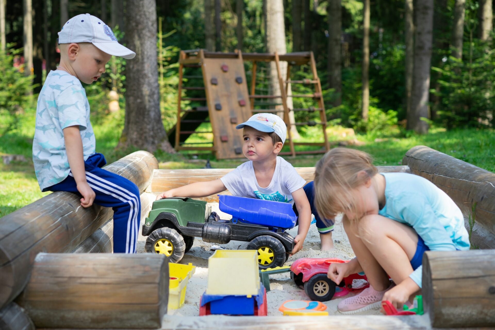 Drei Kinder spielen gemeinsam draussen im Sand