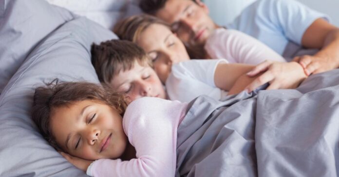 Eine vierköpfige Familie liegt im Bett.