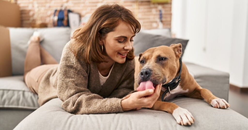 Eine Frau liegt mit ihrem Hund auf dem Sofa.