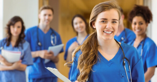 Berufstätige im Gesundheitsbereich lernen für ihre Ausbildung und schauen mit Unterlagen in den Händen in die Kamera