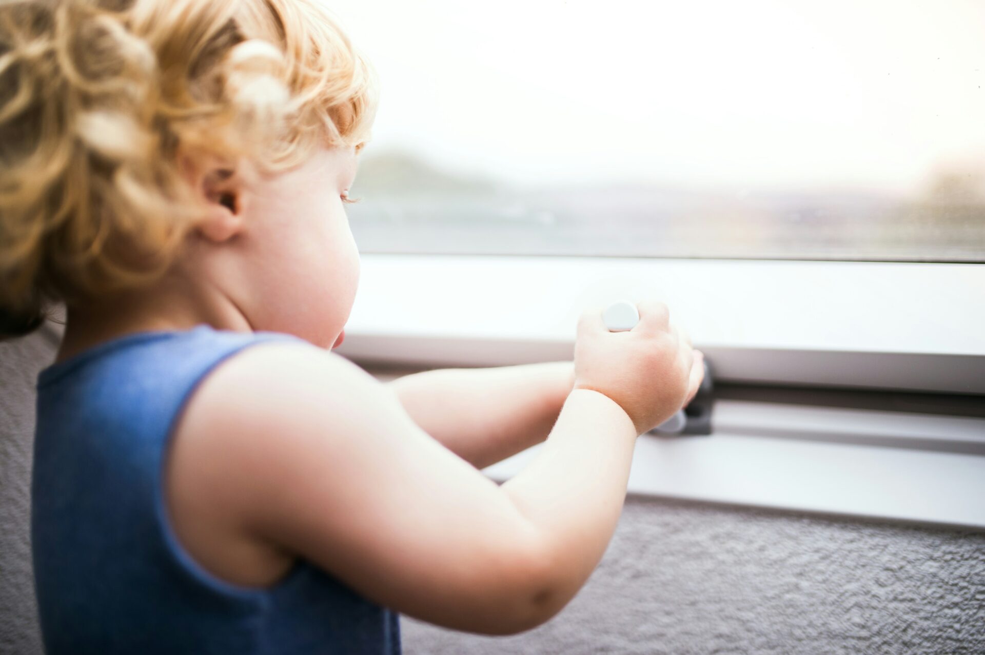 Kleinkind steht zu Hause an einem Fenster