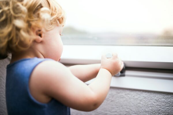 Kleinkind steht zu Hause an einem Fenster
