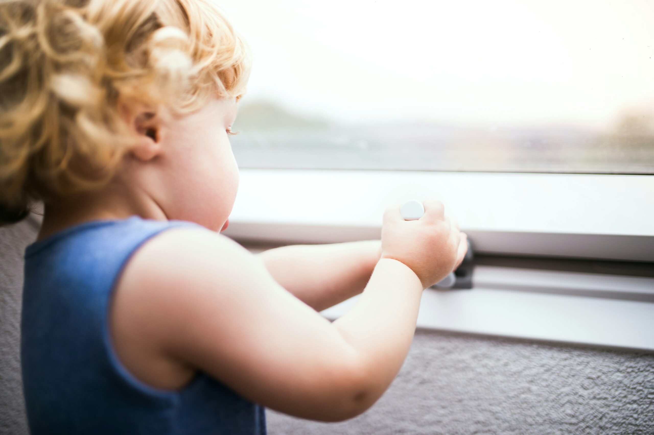 Kleinkind steht zu Hause an einem Fenster