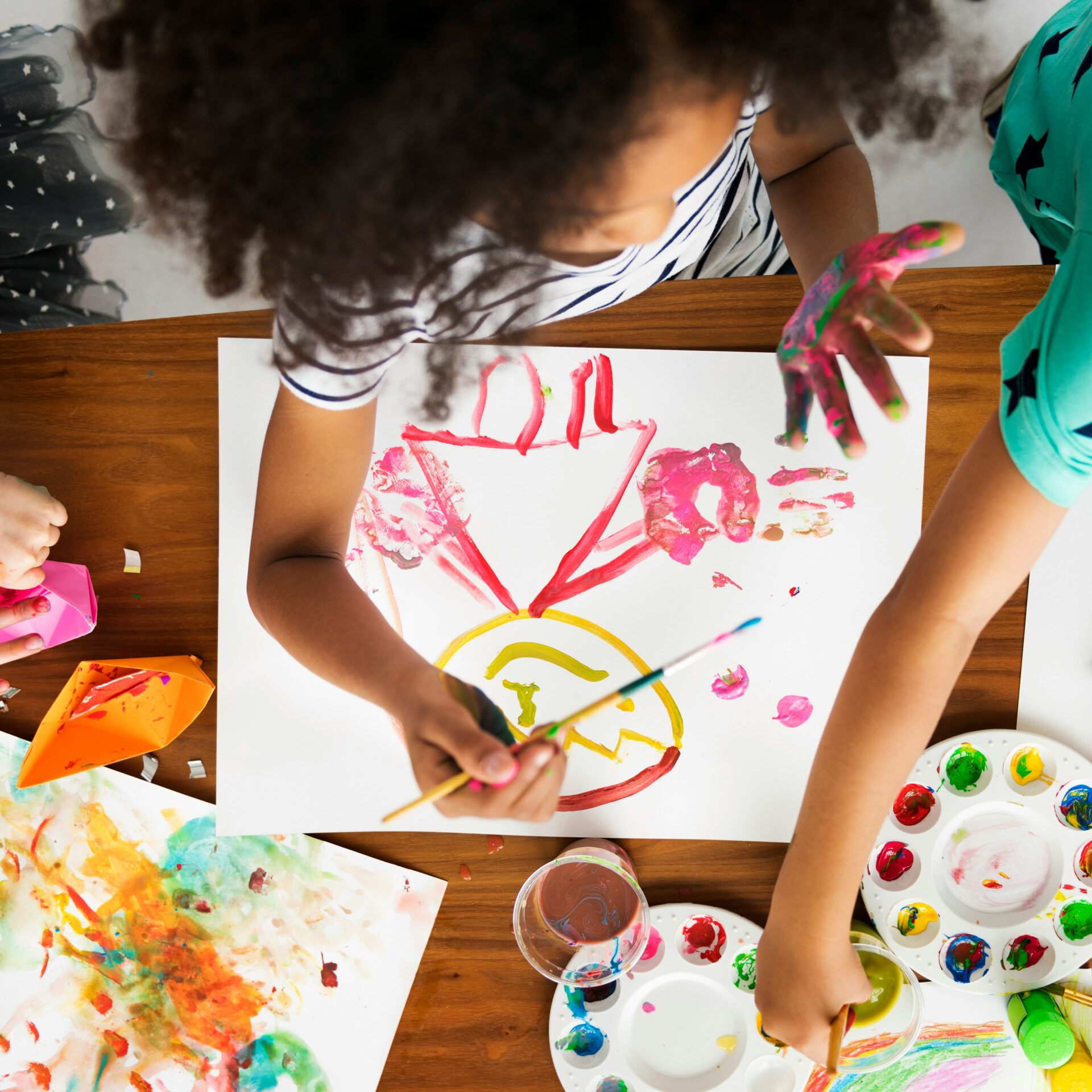 Kinder malen gemeinsam und gestalten ein Bild