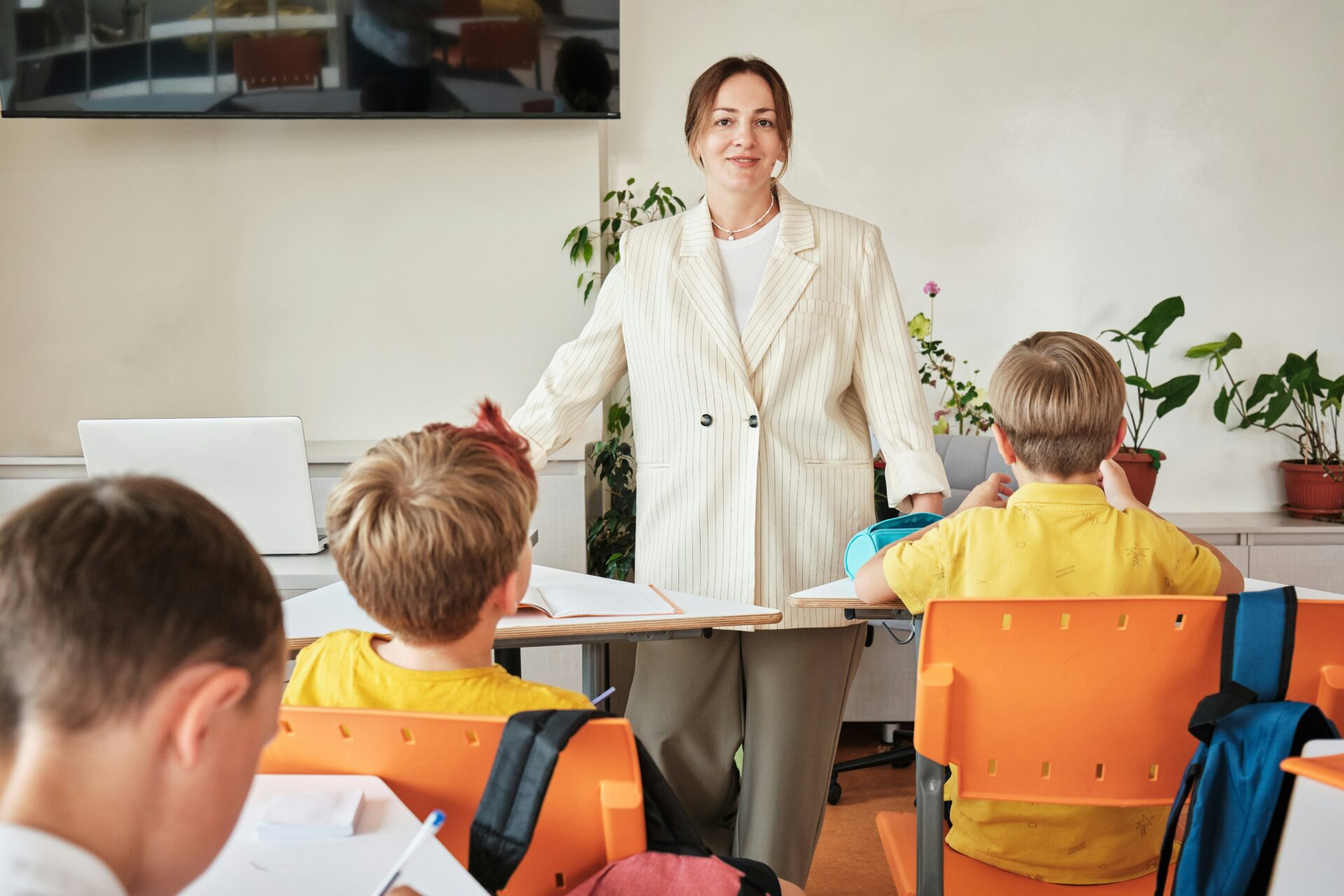 Lehrperson steht vor Schülerinnen und Schülern im Klassenzimmer
