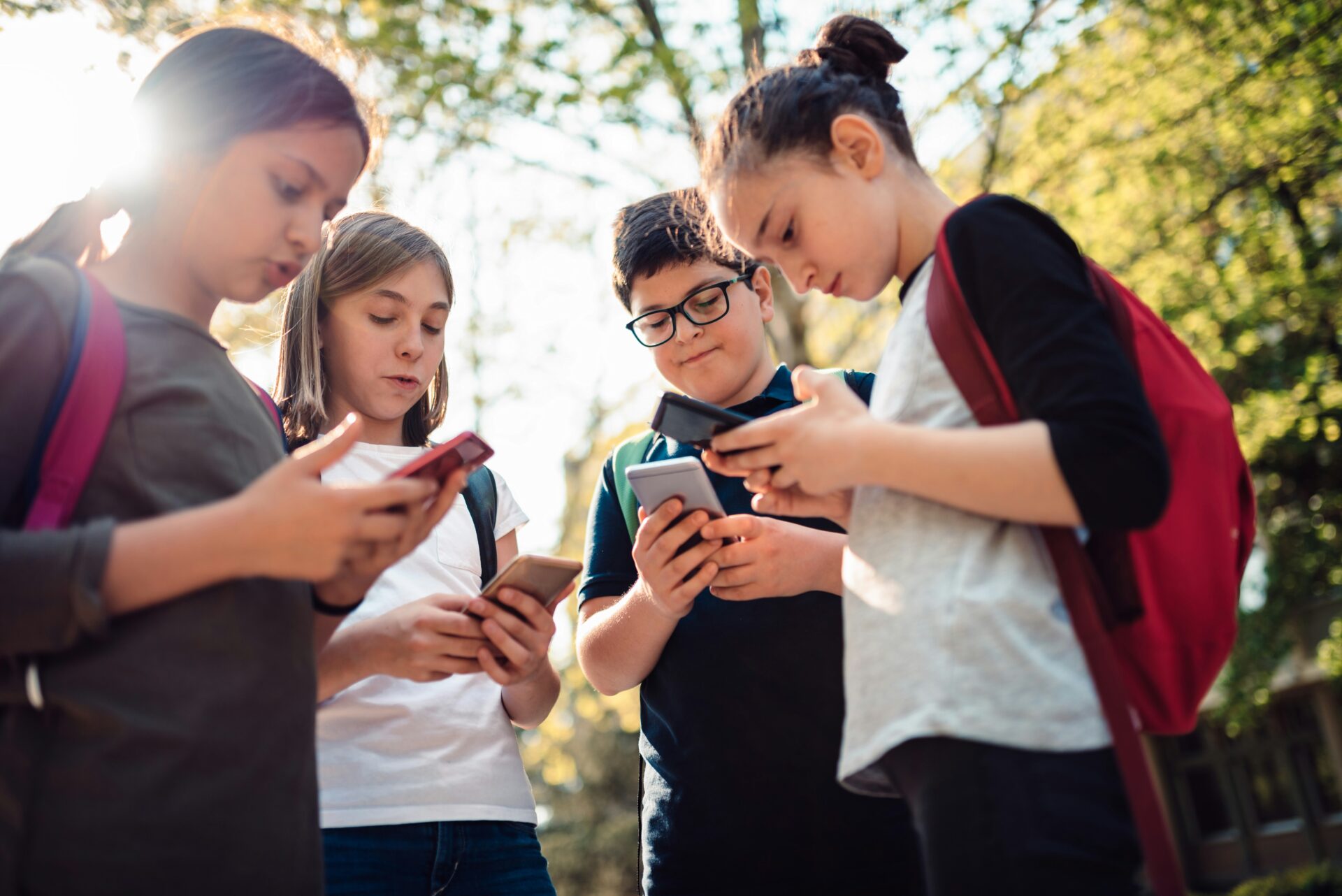 Schulkinder mit Smartphones auf dem Schulweg