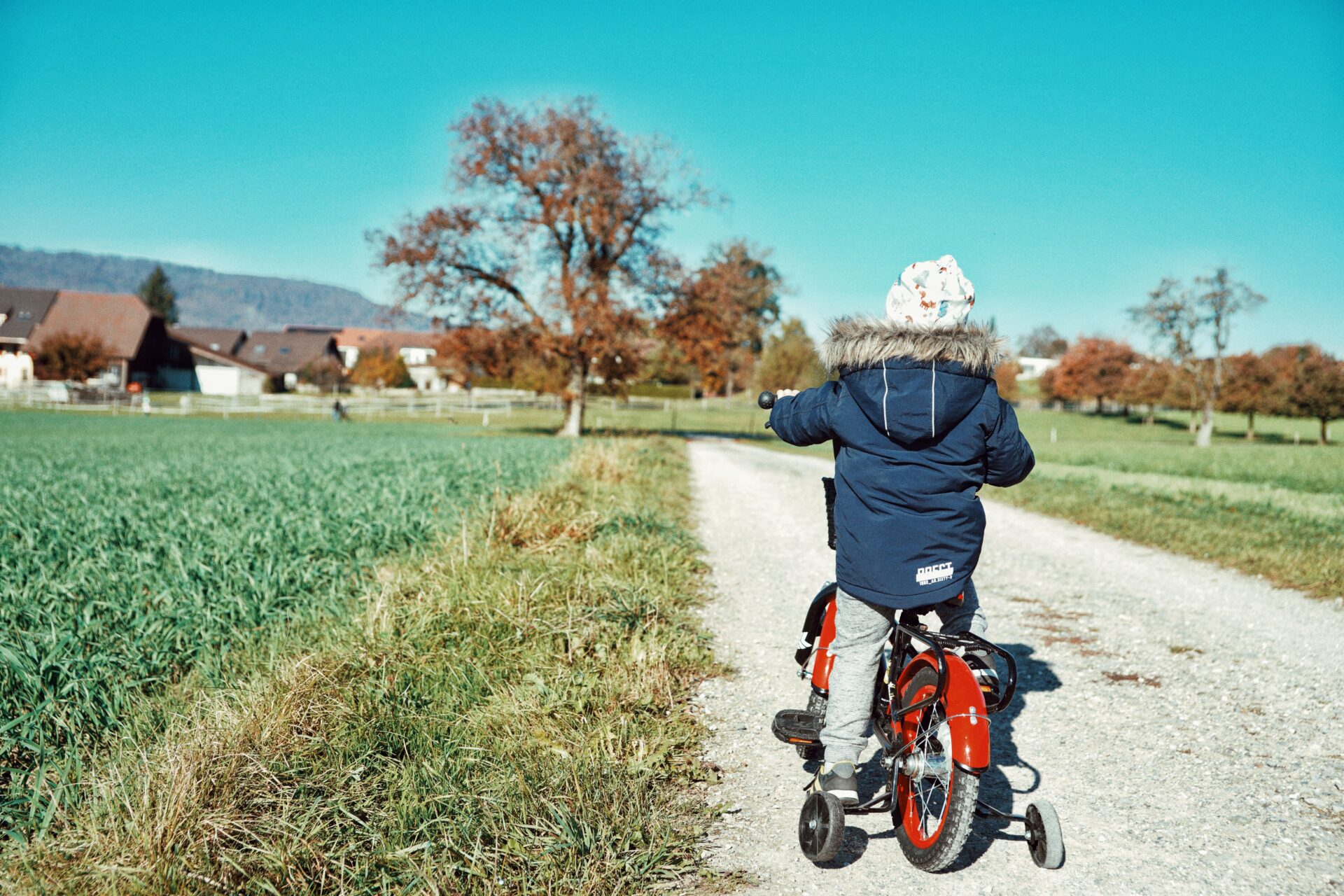 Kind fährt mit einem Fahrrad auf einem Weg durch ein Wohnumfeld