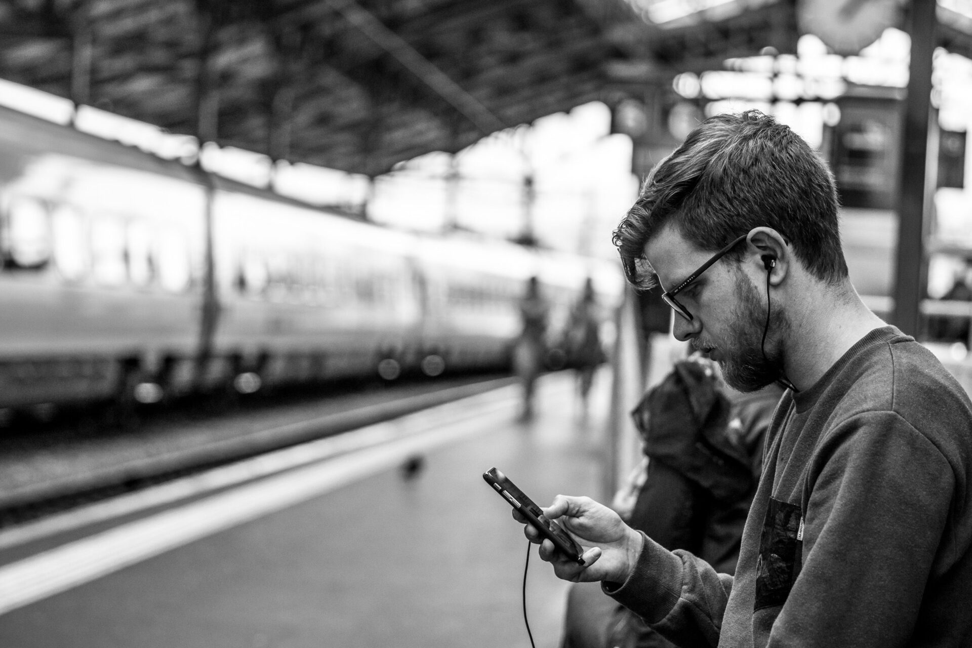 Mann schaut am Bahnhof auf sein Smartphone