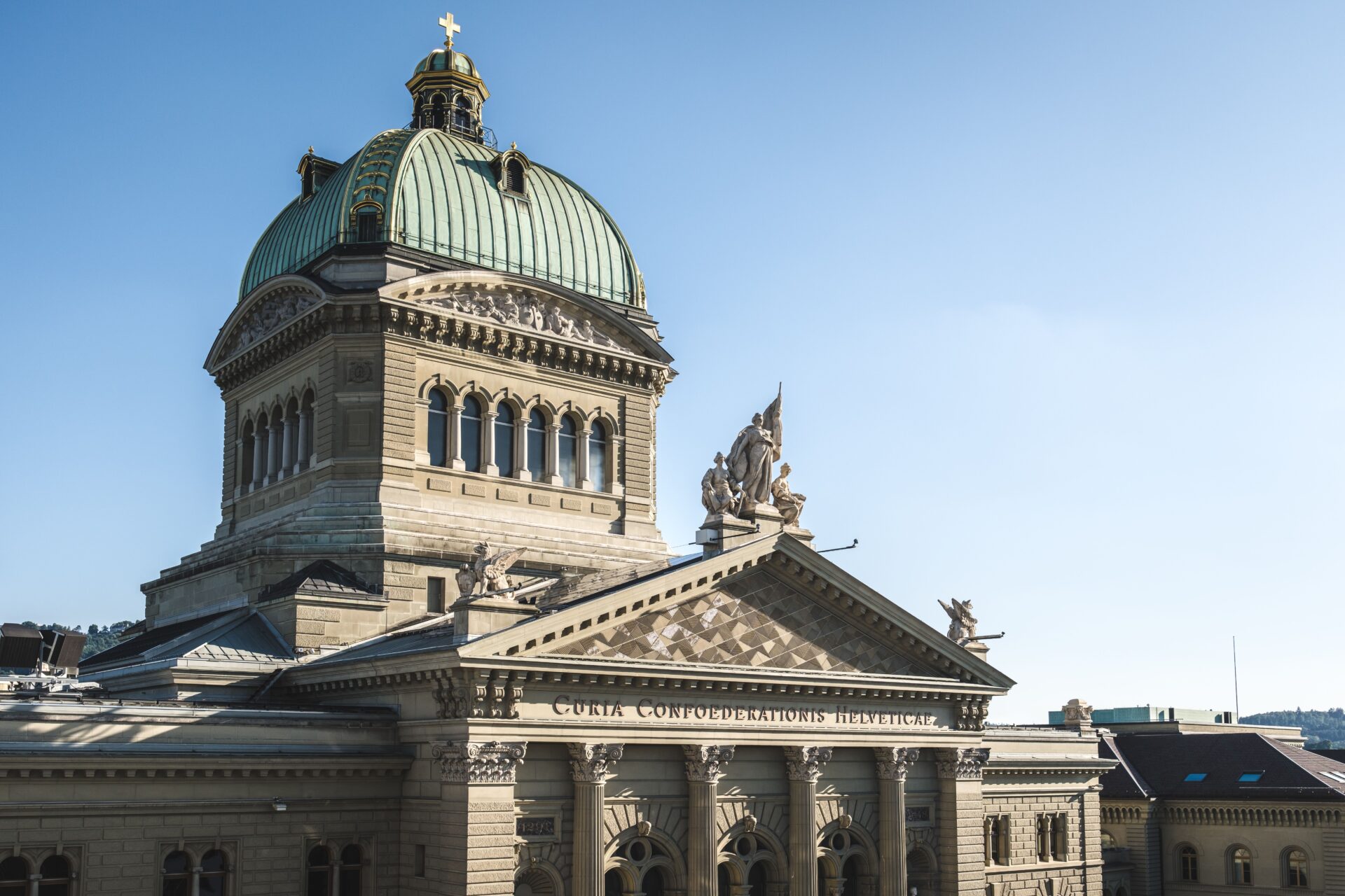 Kuppel und Fassade des Bundeshauses in Bern bei blauem Himmel.