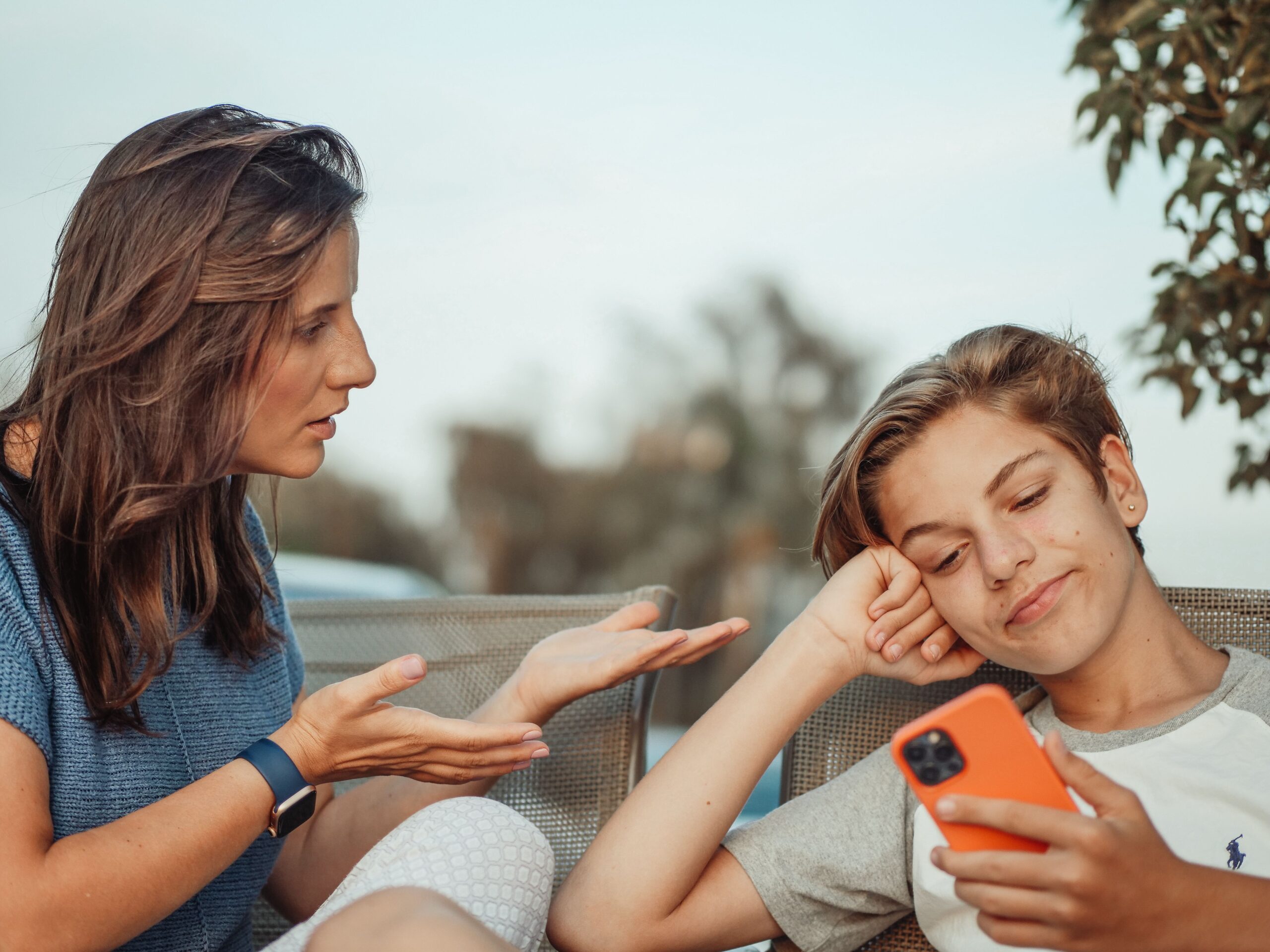 Jugendlicher mit Smartphone im Gespräch mit seiner Mutter