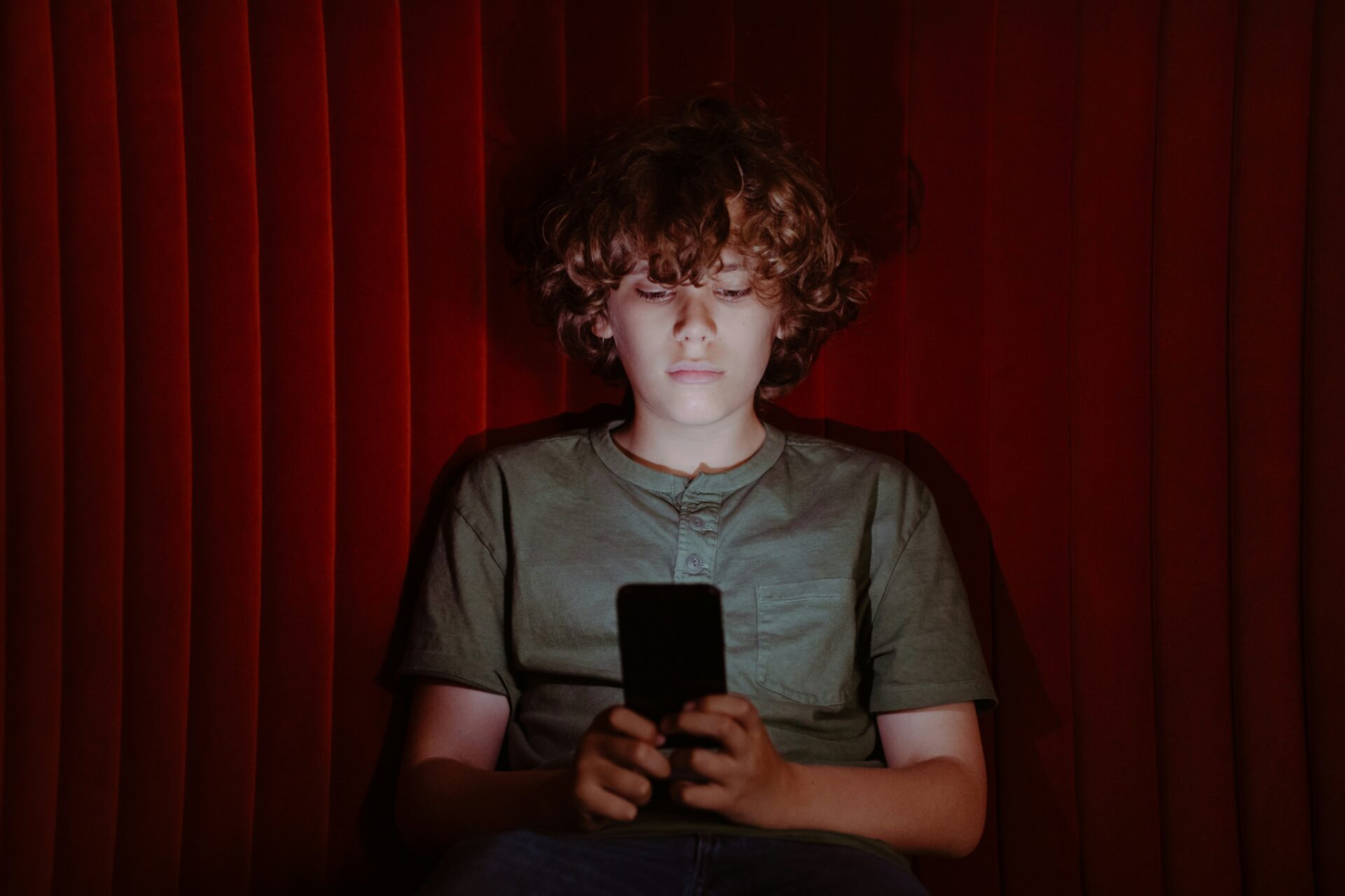 Junge blickt auf ein Smartphone, dessen Display sein Gesicht beleuchtet.