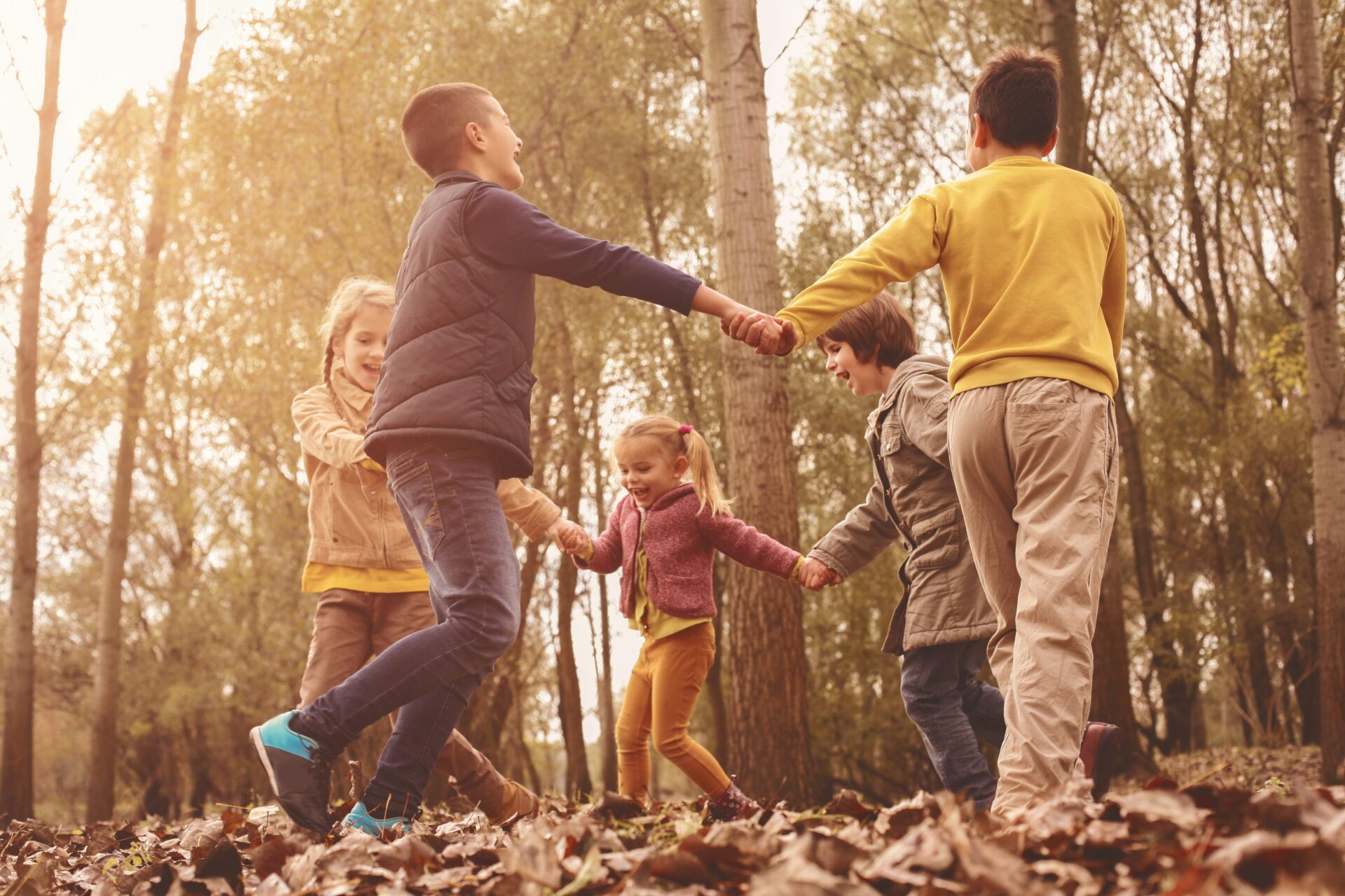 Kinder spielen gemeinsam im herbstlichen Wald