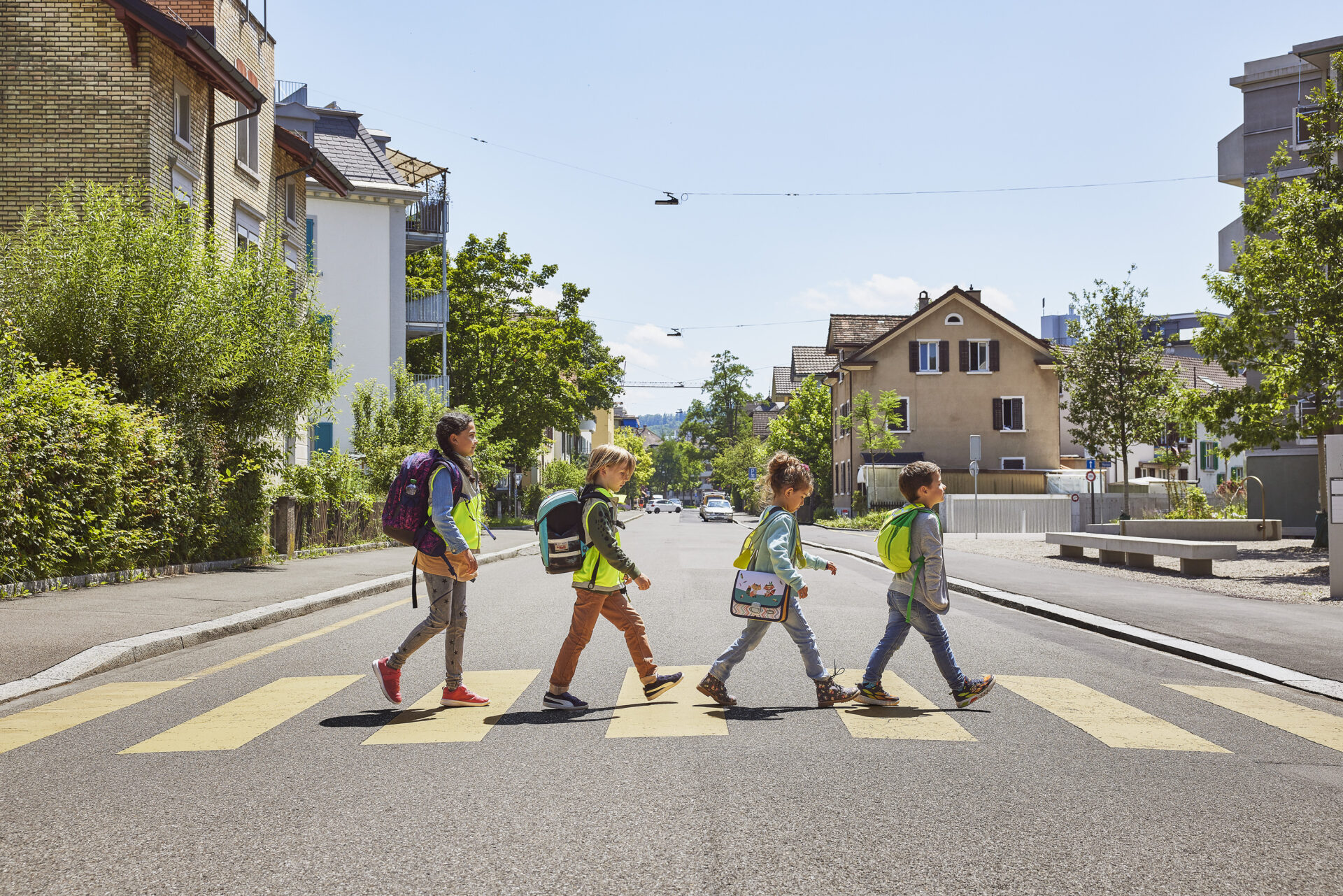 Vier Kinder überqueren auf dem Schulweg einen Fussgängerstreifen