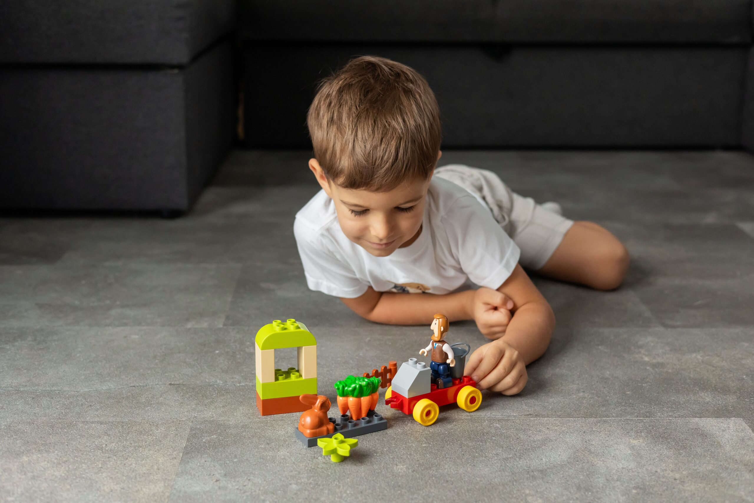 Junge spielt auf dem Boden mit bunten Bausteinen und Spielfiguren